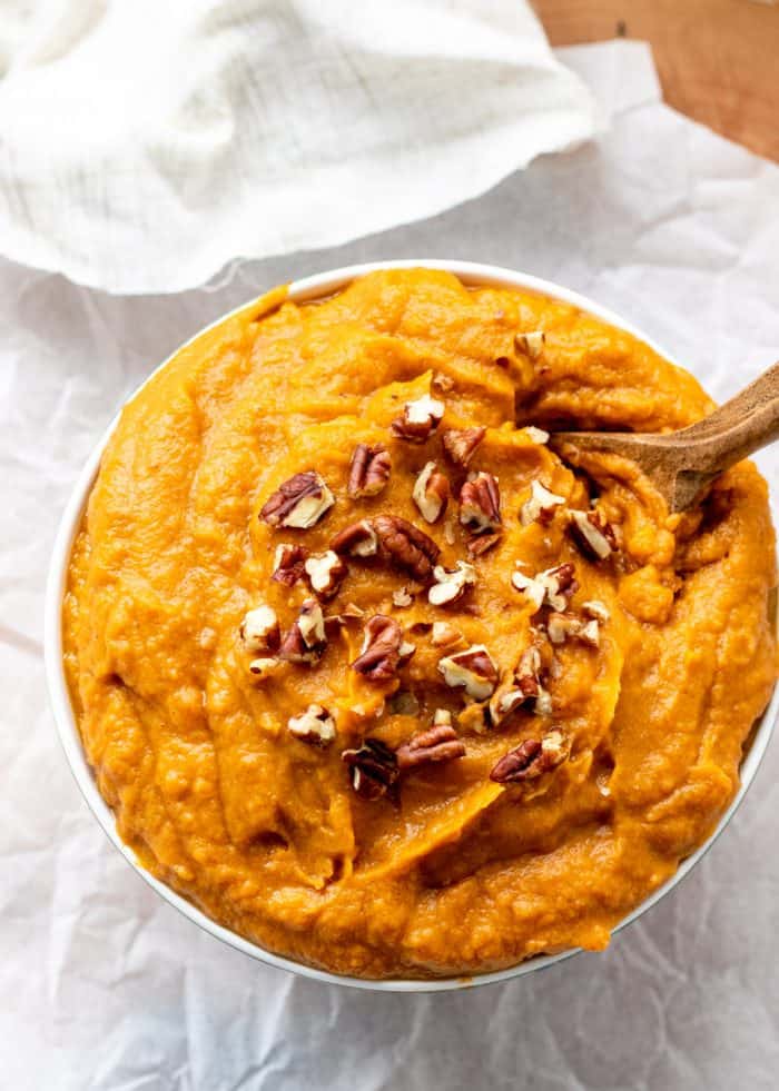 Healthy sweet potato mash in a bowl with a wooden spoon