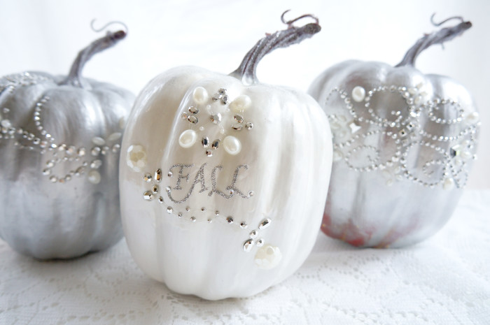Three shiny pumpkins decorated with embellishments and the word \"Fall\"