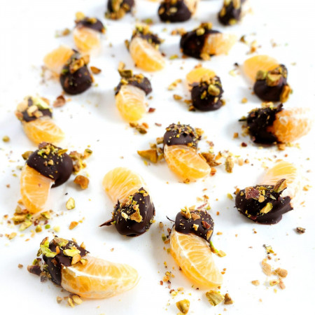 Chocolate Dipped Clementines with Chopped Pistachios on a white surface
