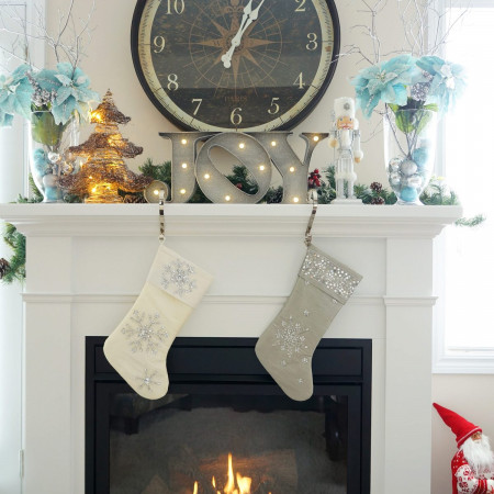Two stockings hung from a mantle with light-up letters J-O-Y