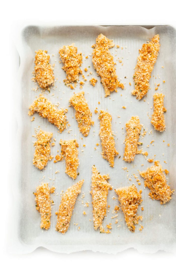 Overhead shot of uncooked Almond Coconut Crusted Fish Sticks on a sheet pan