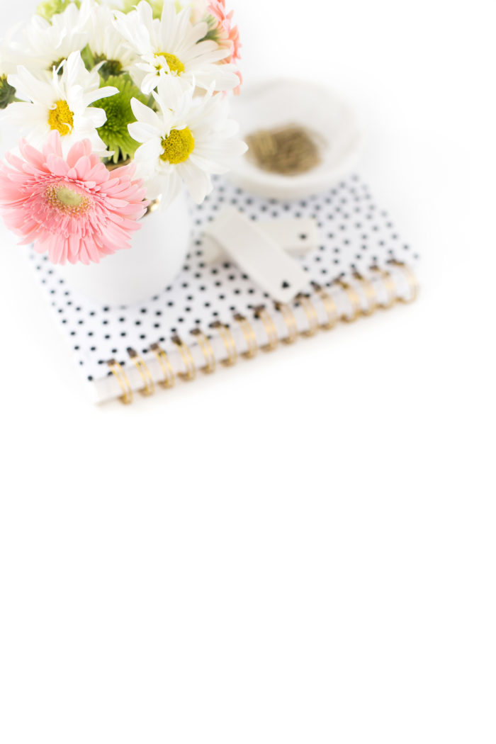 Vase of flowers on a white notebook with black polka dots