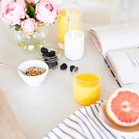 Small bowls of food with a grapefruit, milk, and orange juice