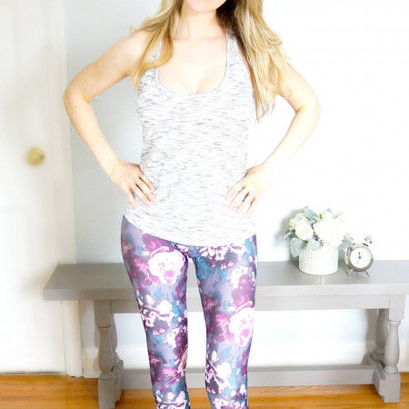 Elysia standing in a grey tank and purple floral leggings