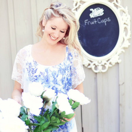 Elysia in a blue and white dress arranging white flowers