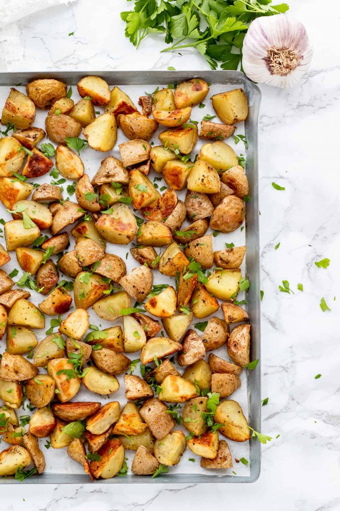 Roasted potatoes on a baking sheet with fresh parsley.