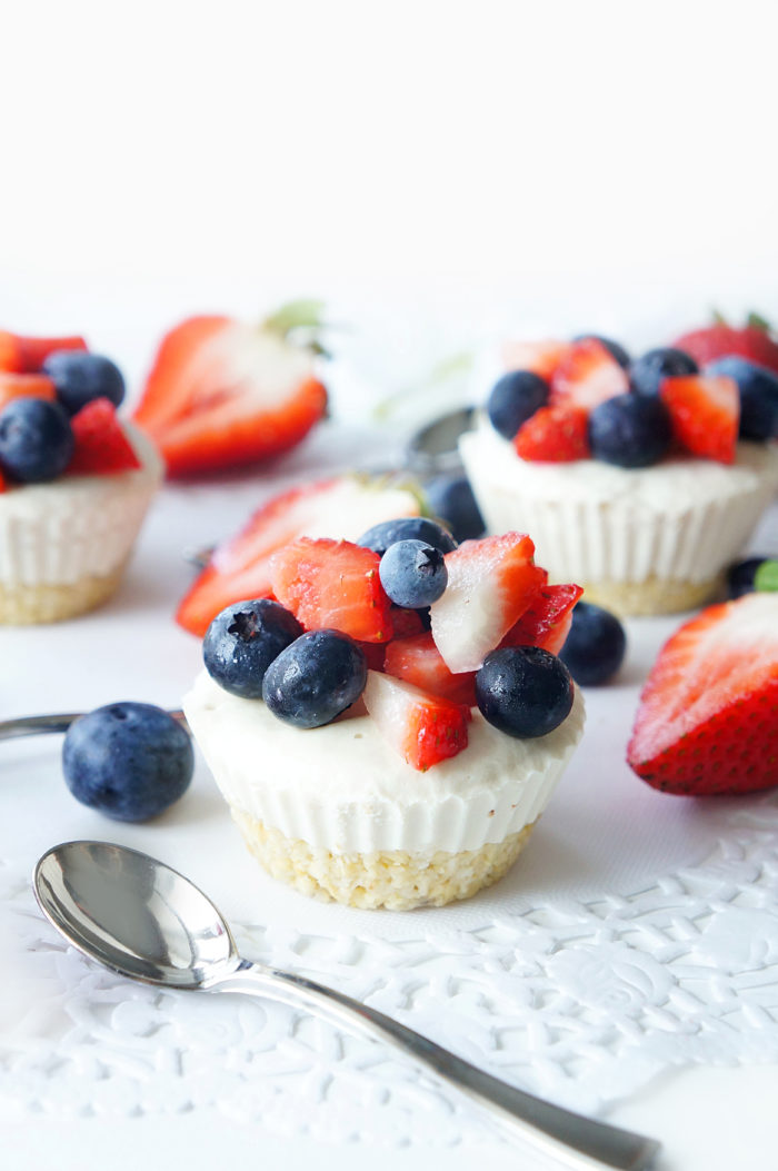 No-Bake Vegan Lemon Berry Cheesecake Cups surrounded by fruit and spoons