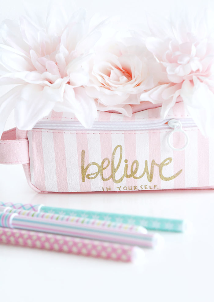 Pink bag that reads \"believe in yourself\" topped with pink flowers