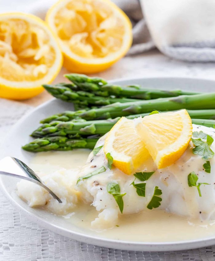 Using fork to eat fish with lemon sauce and asparagus