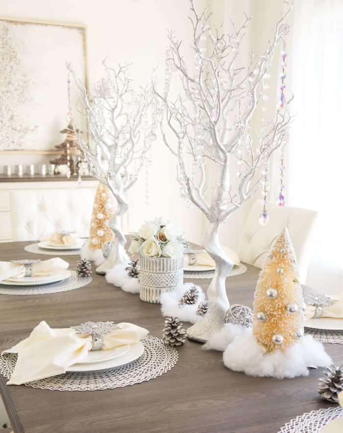 Elegant table set with tall silver trees, sparkly pine cones, and other decorations