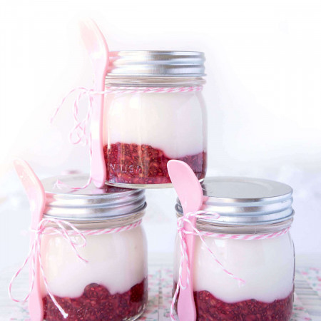Pyramid of three Homemade Raspberry Fruit-on-the-Bottom Yogurt Mason Jars tied with pink spoons