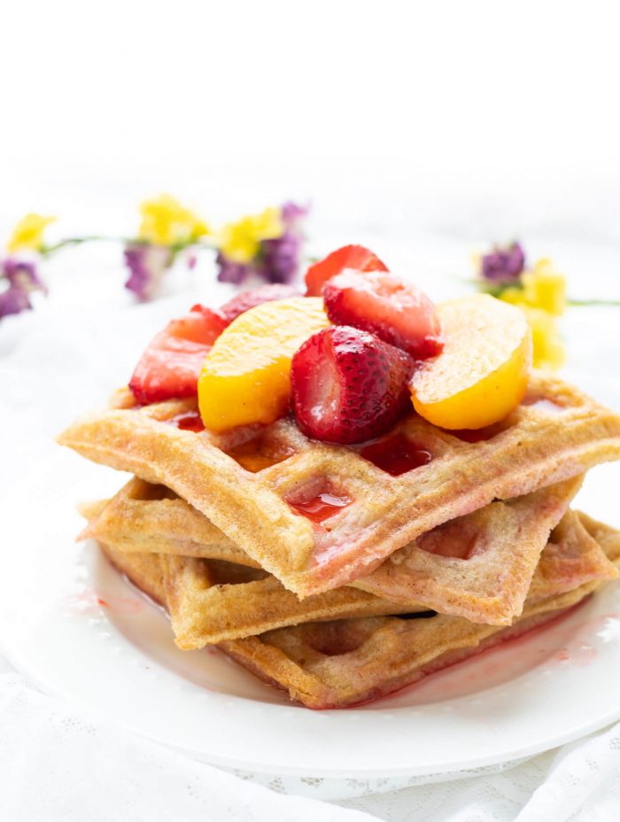 Closeup of a stack of Paleo Waffles piled with fruit on a plate