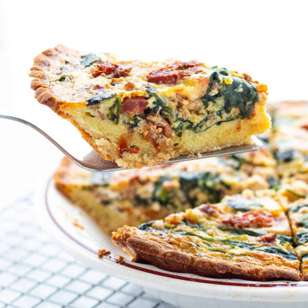 slice of low carb spinach bacon quiche on spatula