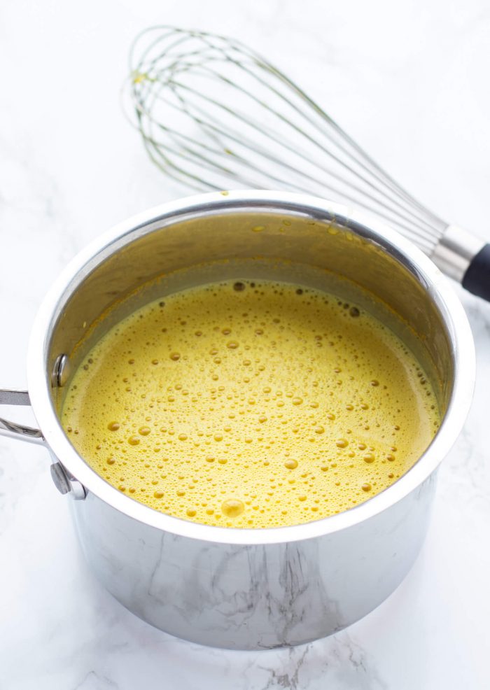 Turmeric latte whisked in a saucepan.