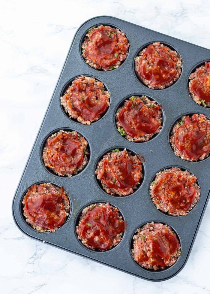 The meatloaf meat in the muffin tin before cooking