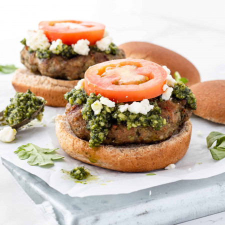 A chicken pesto burger without the top bun on the toppings