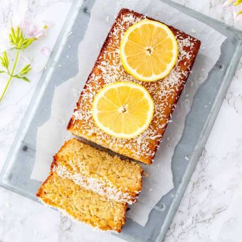 Lemon coconut loaf topped with lemon slices with two slices of the loaf cut.