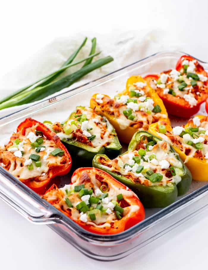 buffalo chicken peppers in a glass baking dish with cheese and green onions