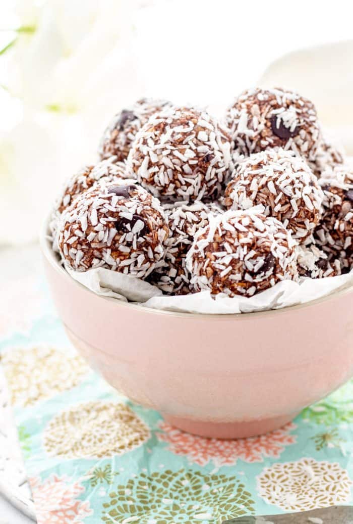 Chocolate bites covered in coconut shreds in a pink bowl.