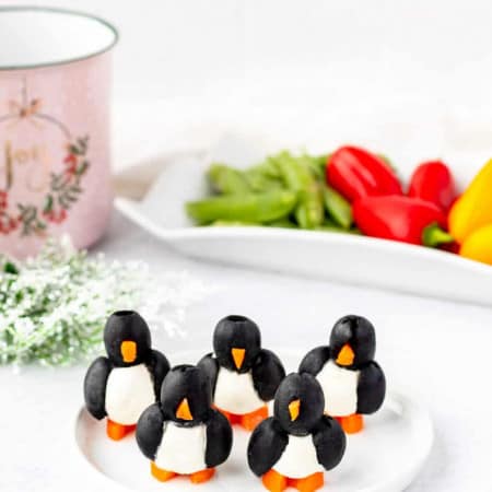 Five olive penguins on a white plate.