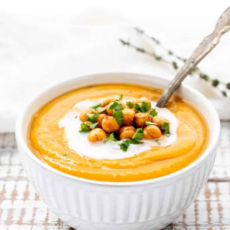 Sweet potato coconut soup in a bowl topped with chickpeas and fresh parsley.