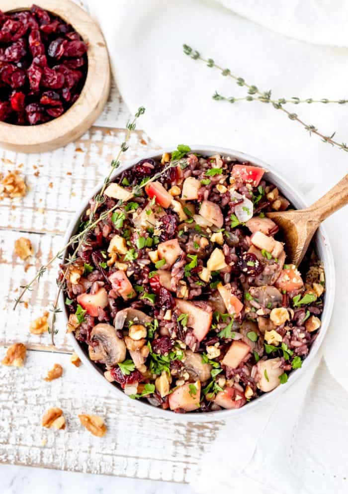 A wooden spoon in a bowl of cranberry wild rice.