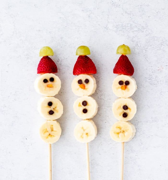 banana slices, strawberries, grapes and mini dark chocolate chips on skewers to make banana snowmen