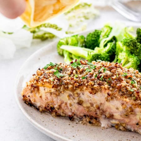 A fillet of baked salmon served in a plate with broccoli.