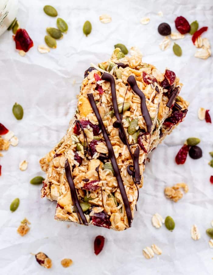 top shot of granola bars with chocolate drizzle, nuts, dried fruit and pumpkin seeds.