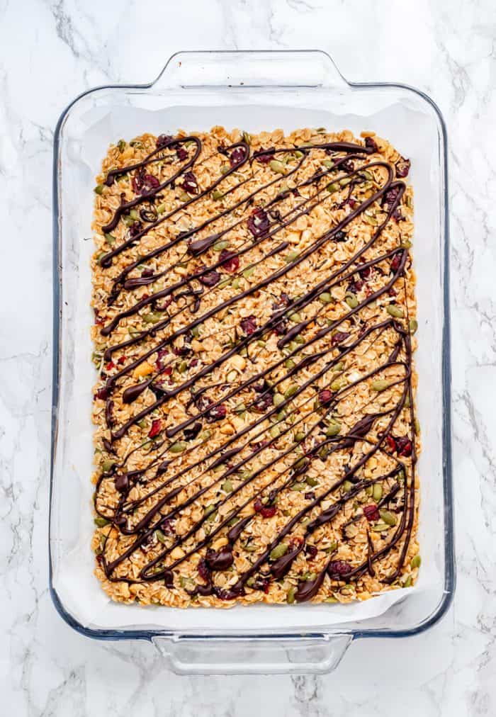 granola bar mixture in a dish with chocolate drizzle