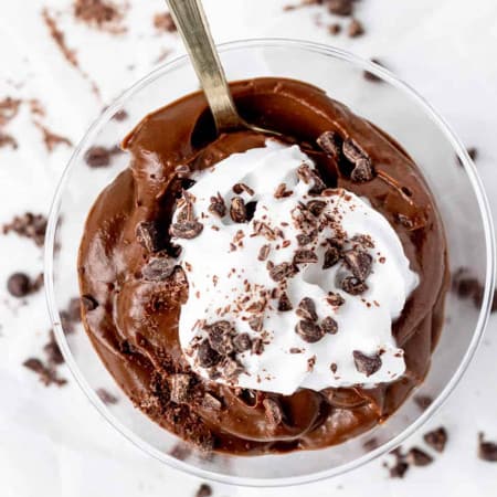 A spoon in a glass of avocado chocolate pudding.