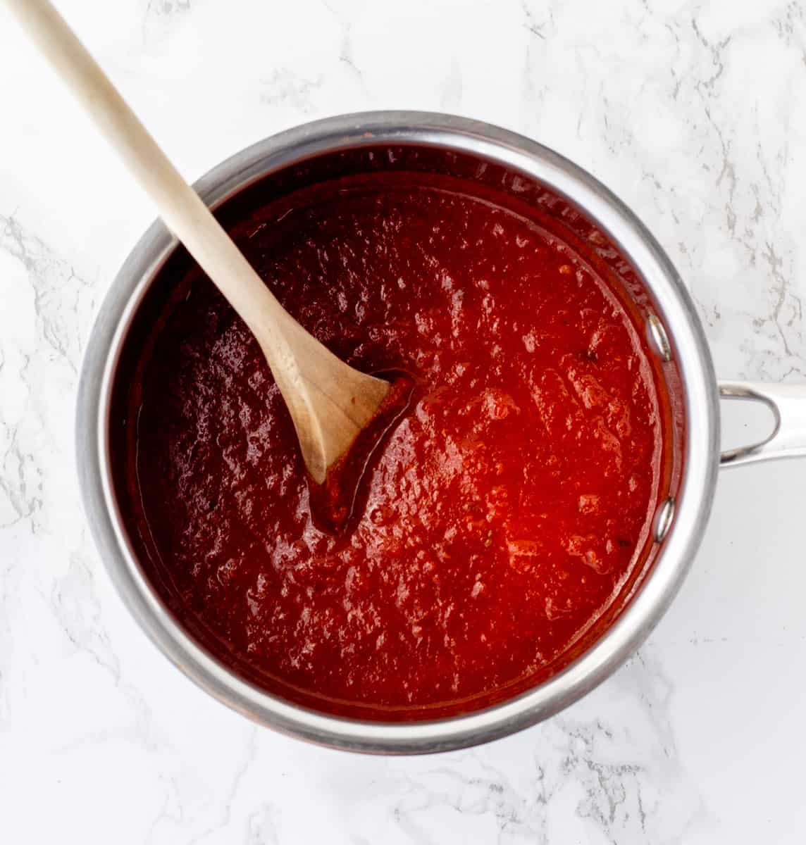 Enchilada sauce in a pot with a wooden spoon.