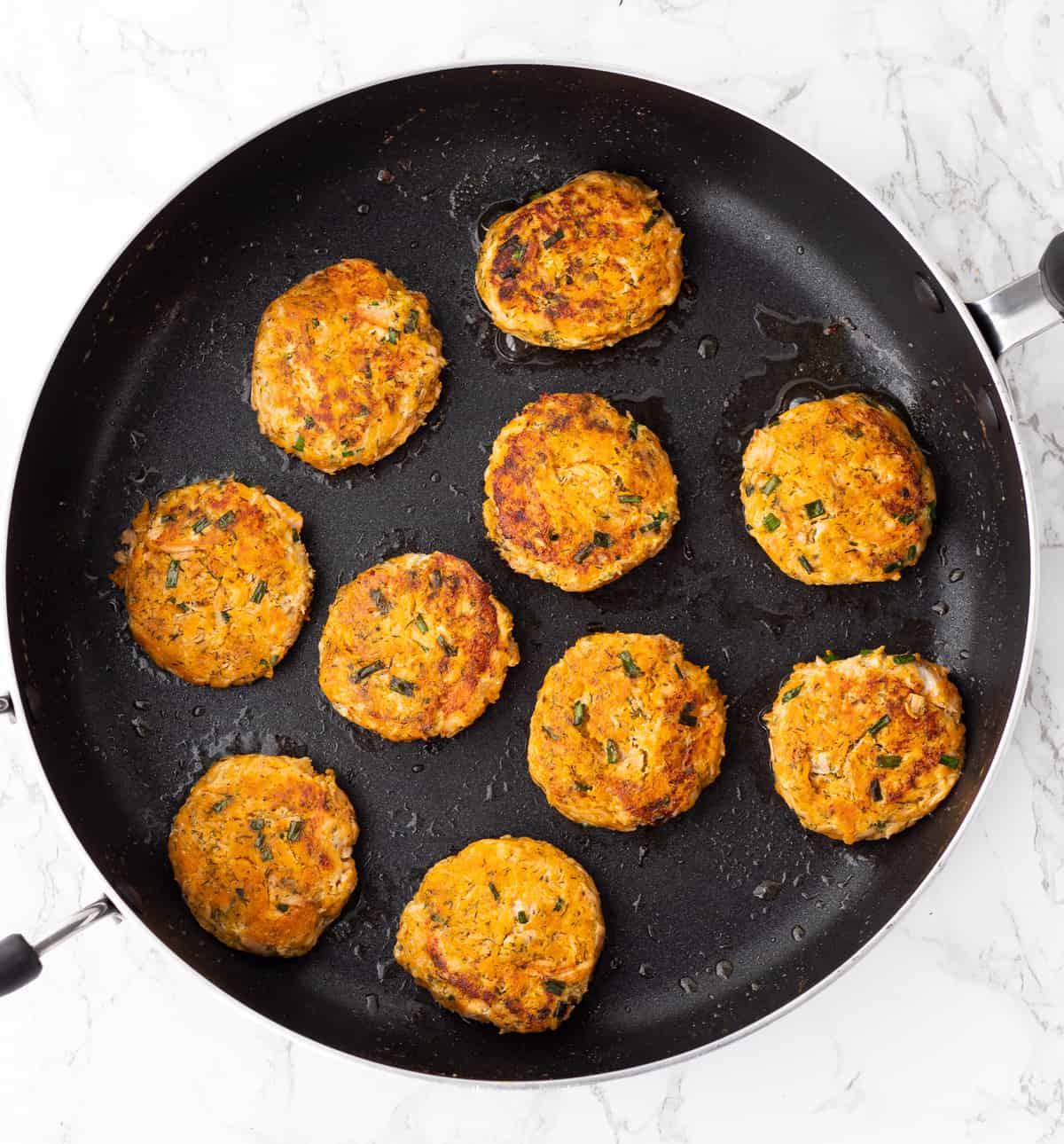 Cooked salmon cakes in a skillet.