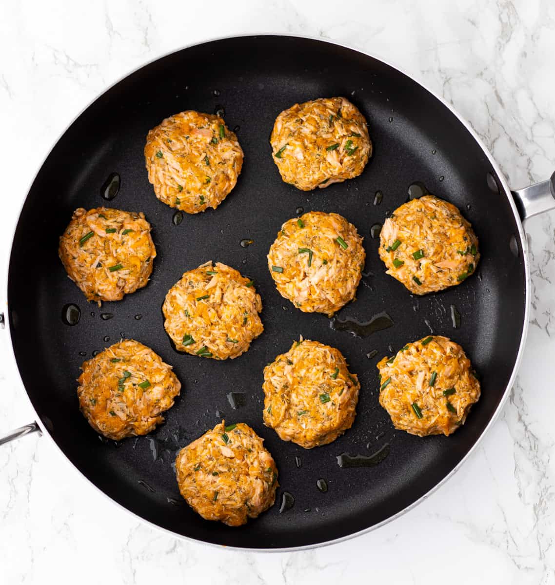 Salmon cakes cooking in a skillet.