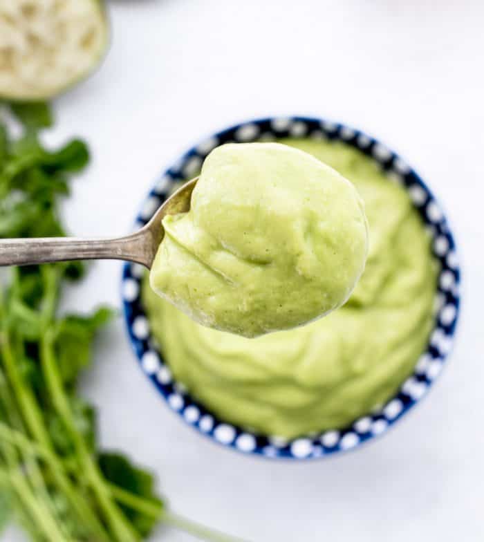 Overhead shot of a spoon in a bowl of the avocado sauce.