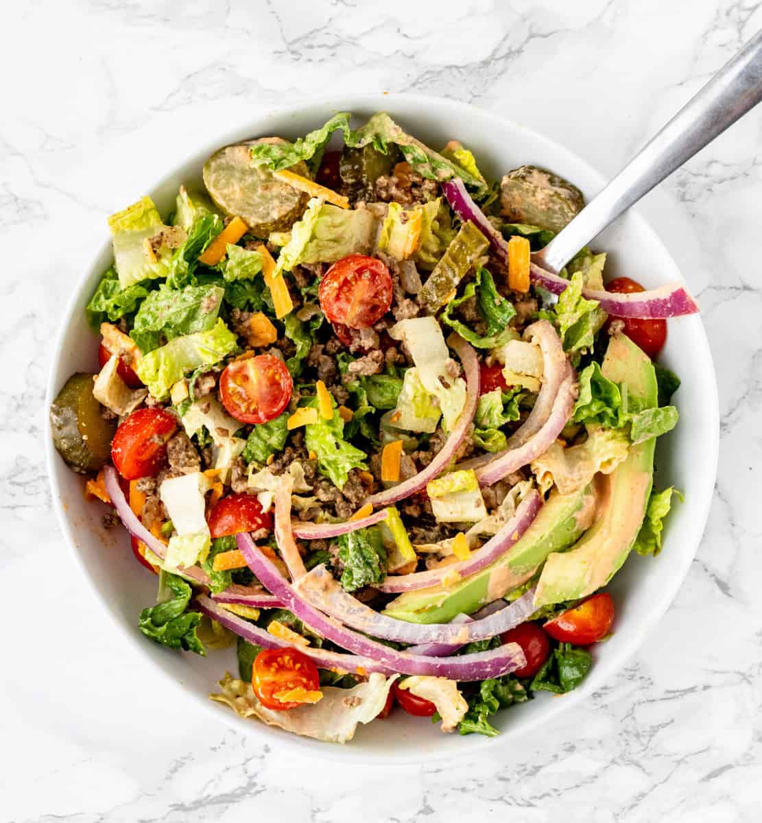 A spoon in a burger bowl salad.