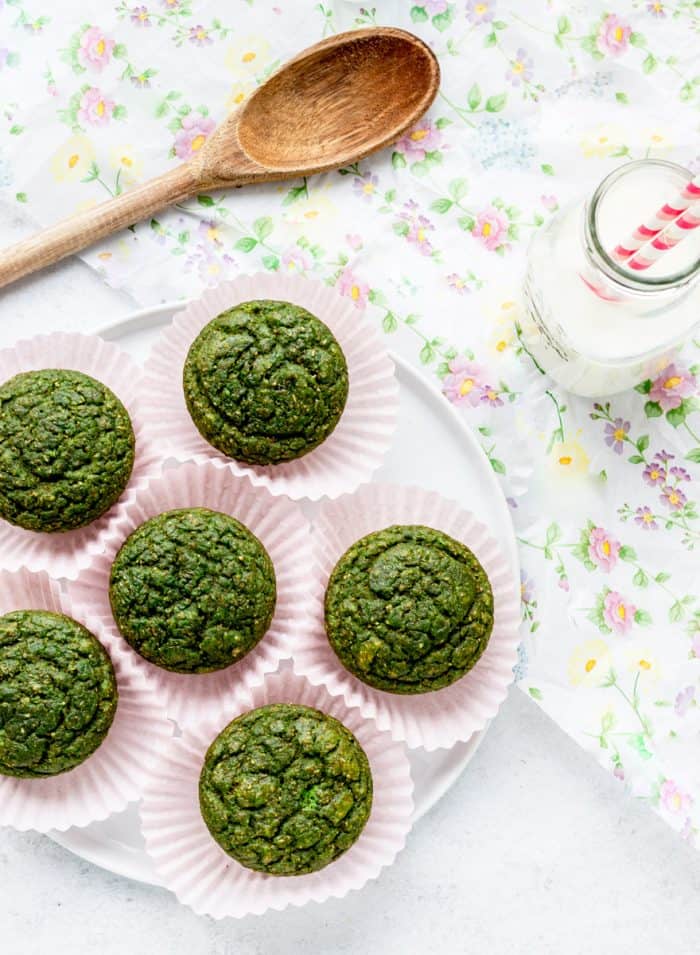 overhead shot of green monster muffins on plate with milk and a wooden spoon
