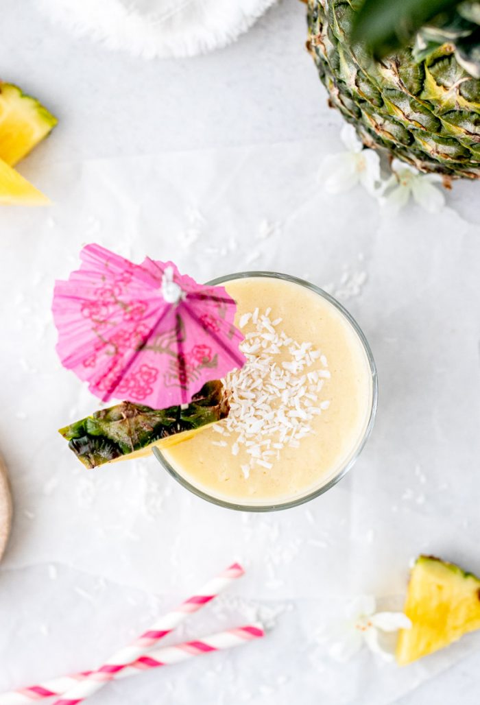 Overhead shot of an umbrella and slice of fresh pineapple in the smoothie.