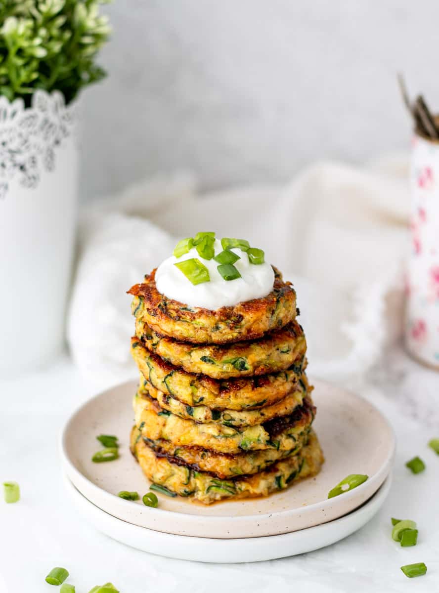 Six zucchini patties topped with sour cream and sliced scallions.