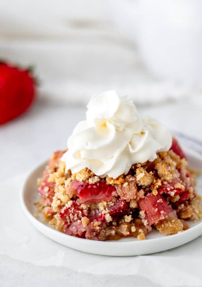 Fruit crumble on a plate served with whipped cream.