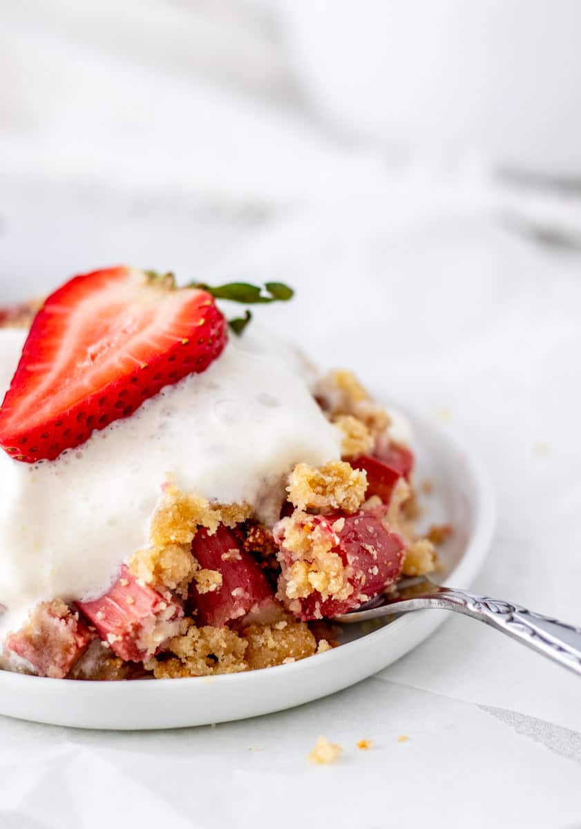 Fruit crumble served in a bowl with a spoon.
