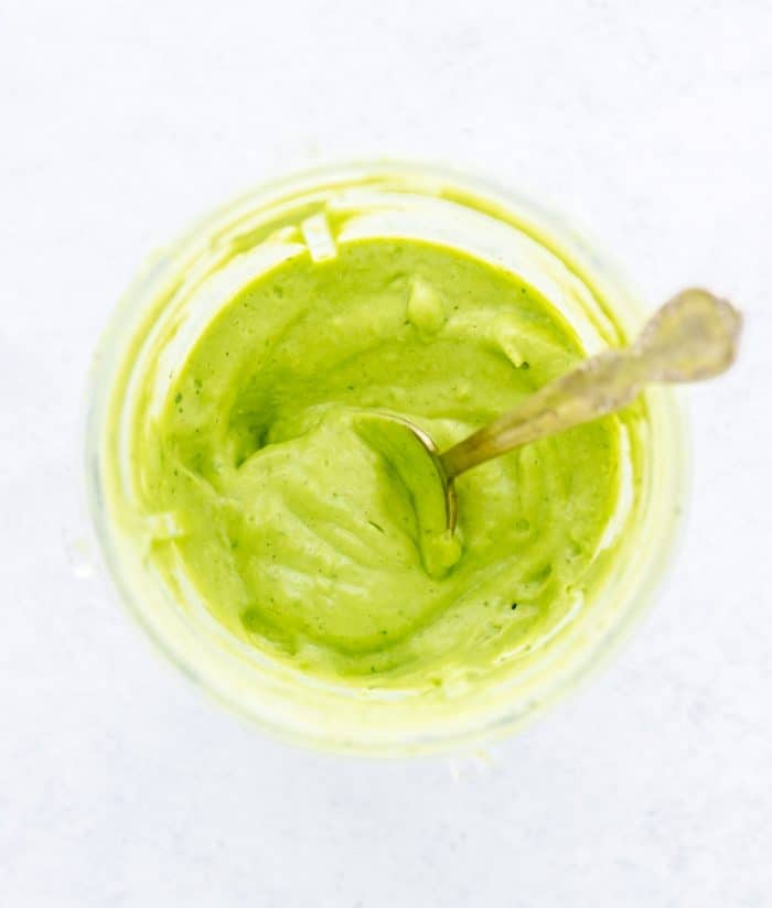 Overhead shot of a spoon in the avocado green goddess dressing.