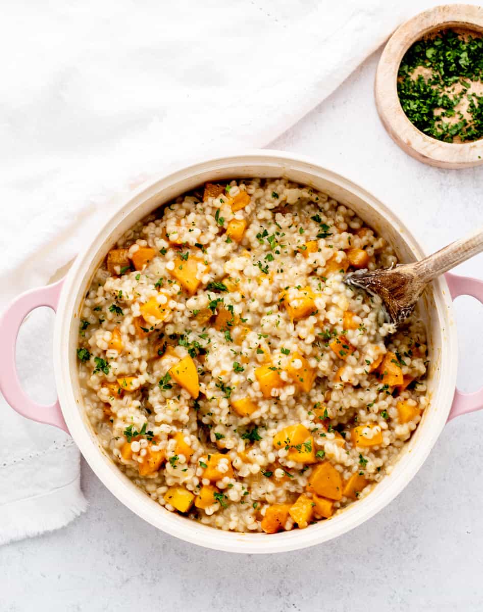 Butternut squash risotto in a large pot with a spoon.