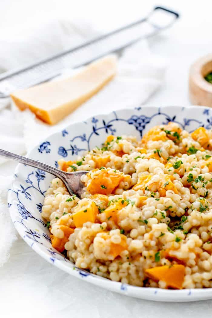 A spoon in a bowl of barley risotto.