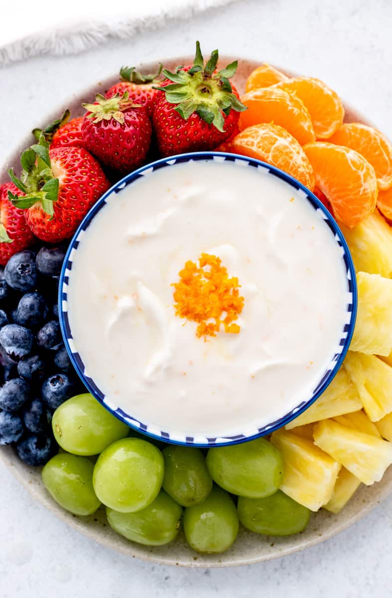 Overhead shot of a fruit yogurt dip in the middle of a platter of fruits.