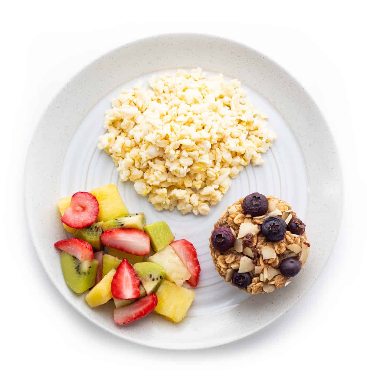 Scrambled eggs with oatmeal muffin and fruit salad on a plate