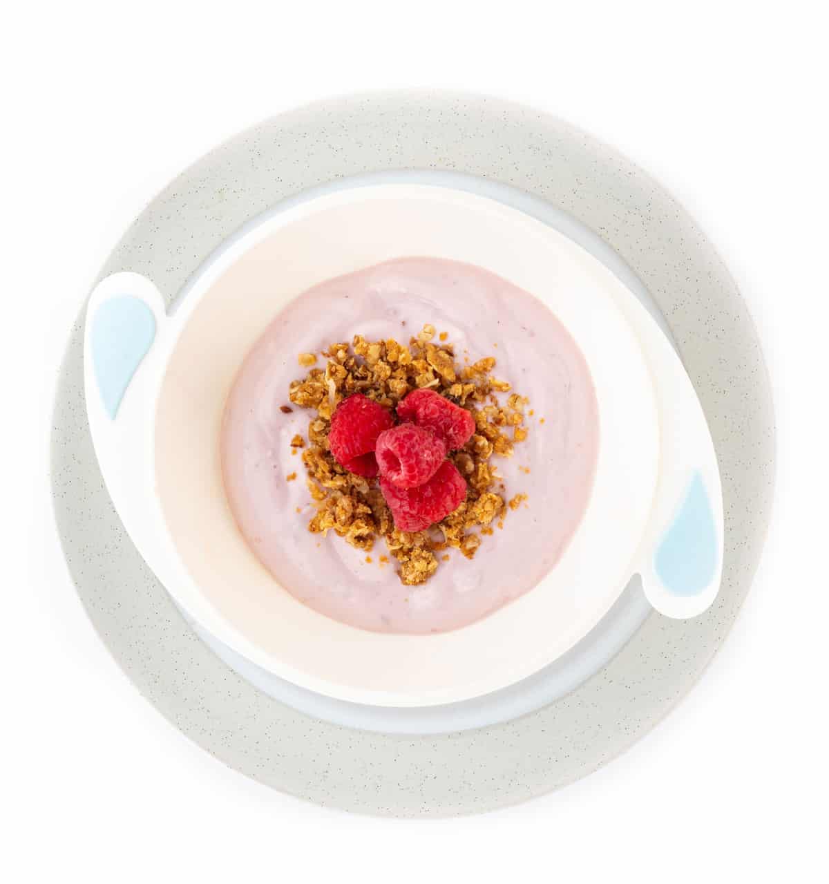 Bowl of yogurt with granola and fresh raspberries on a plate