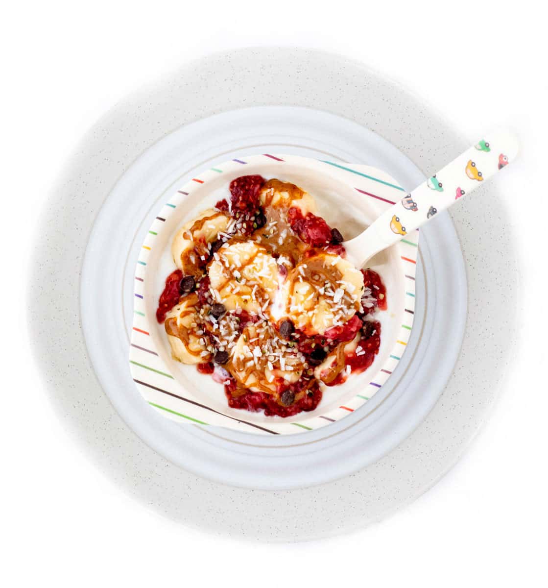 Banana split yogurt bowl with a spoon on a plate