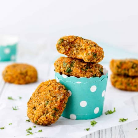 Vegan quinoa patties in turquoise cups with one leaning against the side