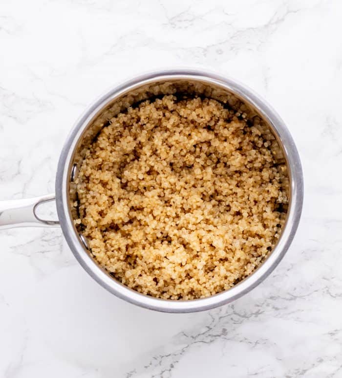 Cooked quinoa in a pot on a marble background